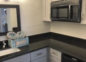 Thumbnail 18 of 18 - a kitchen with white cabinets and black countertops at Colonial Apartments, Orlando Florida