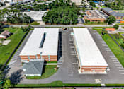 Thumbnail 11 of 17 - A large parking lot is surrounded by a building and a grassy area.