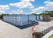Thumbnail 15 of 17 - A large white building with a black fence and a yellow sign with red letters.