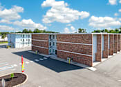 Thumbnail 10 of 17 - A parking lot with a building and a flag.