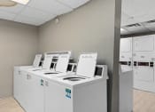 Thumbnail 17 of 39 - a row of washers and dryers in a laundry room at Emerald Greens, Norman, 73072