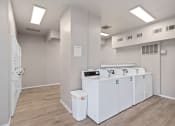 Thumbnail 16 of 39 - a community laundry room with four washers and dryers and a row of sinks at Emerald Greens, Norman, OK