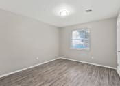 Thumbnail 28 of 39 - an empty room with wood flooring and a window at Emerald Greens, Oklahoma, 73072