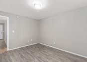Thumbnail 34 of 39 - an empty living room with wood flooring and white walls at Emerald Greens, Oklahoma