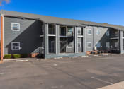 Thumbnail 21 of 39 - a gray apartment building with stairs and a parking lot at Emerald Greens, Oklahoma, 73072