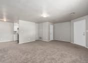 Thumbnail 27 of 39 - an empty living room with carpet and a white kitchen at Emerald Greens, Oklahoma 