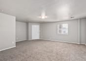 Thumbnail 22 of 39 - an empty living room with carpet and a white door at Emerald Greens, Norman, OK 73072