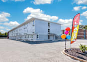 Thumbnail 6 of 17 - A white building with a sign that says "LEASING" in front of it.