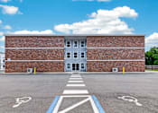 Thumbnail 16 of 17 - A parking lot with a building in the background and a crosswalk in the foreground.