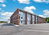 Thumbnail 12 of 17 - A large parking lot in front of a multi-story brick building.