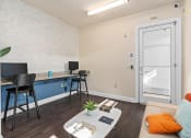 Thumbnail 49 of 51 - a living area with a couch and a desk with chairs and a door to a at Lake Lofts at Deerwood, Jacksonville, FL, 32216