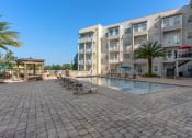 Thumbnail 2 of 51 - a large swimming pool in front of an apartment building at Lake Lofts at Deerwood, Jacksonville, FL, 32216