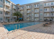 Thumbnail 16 of 51 - a swimming pool in front of an apartment building at Lake Lofts at Deerwood, Jacksonville, FL