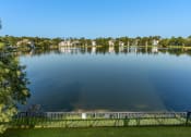 Thumbnail 22 of 51 - a view of a lake with a fence and houses in the background at Lake Lofts at Deerwood, Jacksonville, FL, 32216