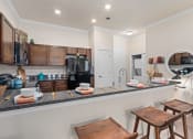 Thumbnail 41 of 51 - a kitchen with a bar and stools in front of a counter with a sink at Lake Lofts at Deerwood, Jacksonville