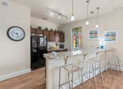 Thumbnail 38 of 51 - a kitchen with a marble counter top and a bar with stools at Lake Lofts at Deerwood, Jacksonville, FL