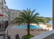 Thumbnail 24 of 51 - a view of a pool and a palm tree in front of an apartment building at Lake Lofts at Deerwood, Jacksonville, 32216