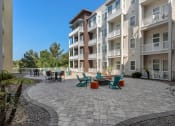 Thumbnail 15 of 51 - an outdoor patio with chairs and tables in front of an apartment building at Lake Lofts at Deerwood, Jacksonville, FL, 32216
