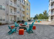 Thumbnail 20 of 51 - an outdoor patio with chairs and a fire pit in front of an apartment building at Lake Lofts at Deerwood, Jacksonville