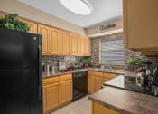 Thumbnail 5 of 21 - a kitchen with black appliances and wooden cabinets at Oak Reserve at Winter Park, Florida, 32792