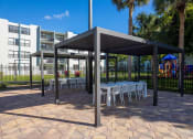 Thumbnail 37 of 54 - a covered patio with tables and chairs  at Club at Emerald Waters, Hollywood, FL, 33021