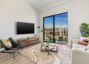 Thumbnail 2 of 27 - A living room with a black chair, a white sofa, a wooden coffee table, and a large window with a view of the city at WM by CLG, Los Angeles, CA  