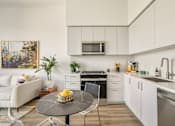 Thumbnail 20 of 27 - A modern kitchen with white cabinets and a black countertop at WM by CLG, Los Angeles  