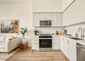 Thumbnail 19 of 27 - A modern kitchen with white cabinets and a stainless steel oven at WM by CLG, Los Angeles, 90232  
