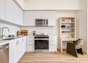 Thumbnail 13 of 27 - A modern kitchen with white cabinets and a wooden shelf at WM by CLG, Los Angeles California  
