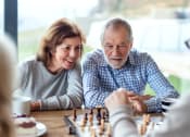 Thumbnail 10 of 17 - an older couple playing a game of chess on a table