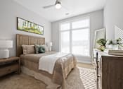 Thumbnail 3 of 34 - A carpeted bedroom with ample natural light from a large window and a ceiling fan.