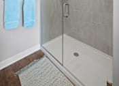 Thumbnail 7 of 34 - A stand-up shower with a frameless door and modern tile walls in a bathroom with hardwood-style flooring.