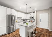 Thumbnail 30 of 34 - A modern kitchen with white cabinets and a wooden floor.