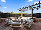 Thumbnail 15 of 34 - An outdoor patio with comfortable furniture, a fire pit, and a pergola.