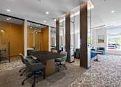 Thumbnail 14 of 34 - Meeting rooms with tables and chairs near a community lounge with comfortable seating and large windows.