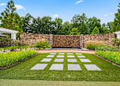 Thumbnail 34 of 59 - A garden with a white lawn and a stone wall.