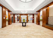 Thumbnail 21 of 59 - A hallway with a table in the middle and a chandelier hanging from the ceiling.