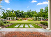 Thumbnail 13 of 59 - A garden with a brick pathway leading to a white archway.