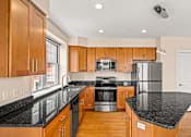 Thumbnail 27 of 59 - A kitchen with wooden cabinets and black countertops.