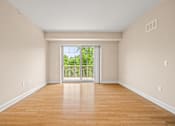 Thumbnail 25 of 59 - A room with wooden floors and a sliding glass door leading to a backyard.