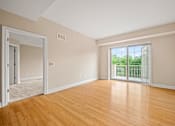 Thumbnail 28 of 59 - A room with wooden floors and a sliding glass door leading to a balcony.