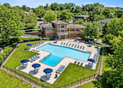 Thumbnail 27 of 64 - A large swimming pool surrounded by lawn chairs and umbrellas.