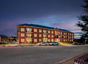 Thumbnail 33 of 39 - A large red brick building with a parking lot in front.