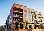 Thumbnail 23 of 34 - River Station's four-story apartment building with balconies and a pergola with trees on the main level.