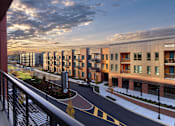 Thumbnail 24 of 34 - A balcony view of River Station's modern apartment building lining a street with the sun setting in the background.