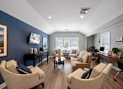 Thumbnail 29 of 30 - A clubhouse with two windows, hardwood-style flooring, comfortable seating areas, and a flat-screen TV.