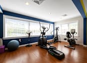Thumbnail 27 of 30 - Cardio machines, a gym ball, and a fan at our state-of-the-art fitness center with many large windows and plenty of light.