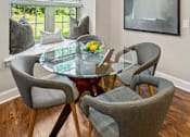 Thumbnail 15 of 30 - A modern dining room with a glass table and grey chairs.