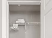 Thumbnail 22 of 30 - A white closet with clothes hanging on a rod.