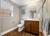 Thumbnail 10 of 30 - A bathroom with a toilet, sink, and wooden floors.